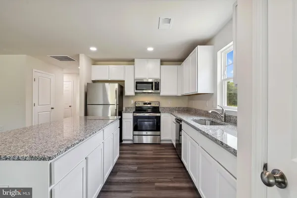a large kitchen with kitchen island granite countertop a large counter top and stainless steel appliances