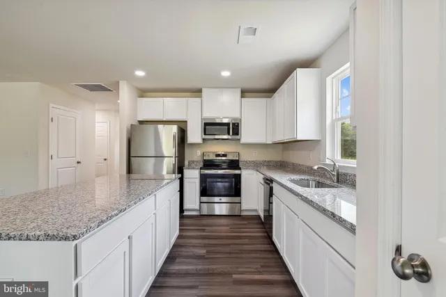 a large kitchen with kitchen island granite countertop a large counter top and stainless steel appliances