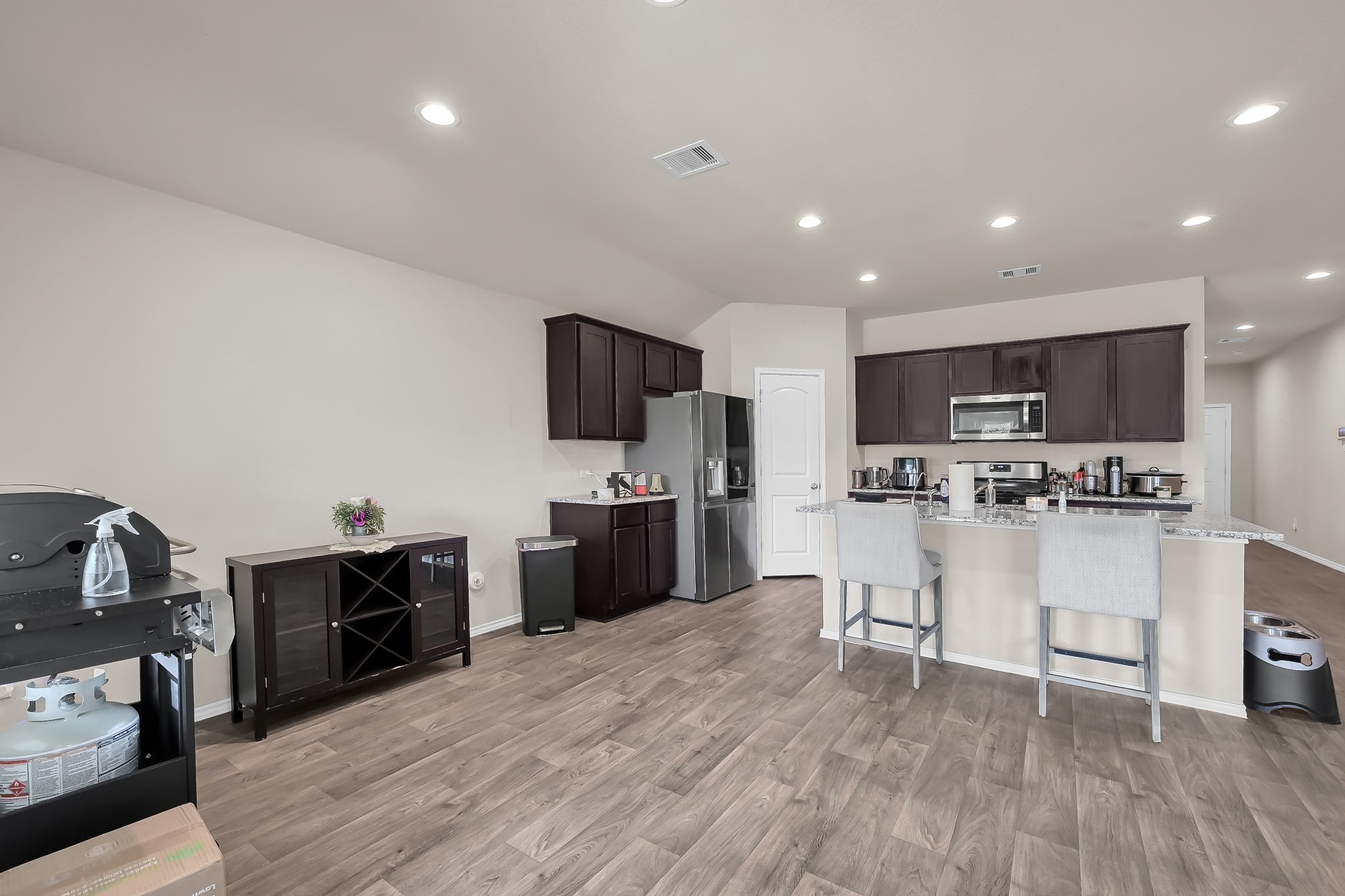 15015 Monserrat Lane Conroe, TX 77304 - Photo 14 of 41 a kitchen with stainless steel appliances kitchen island granite countertop a stove top oven a sink dishwasher a refrigerator and white cabinets with wooden floor