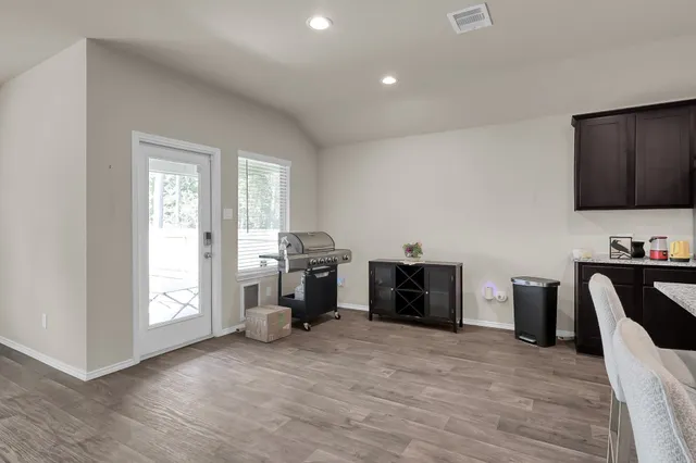 a view of an empty room with a window and wooden floor