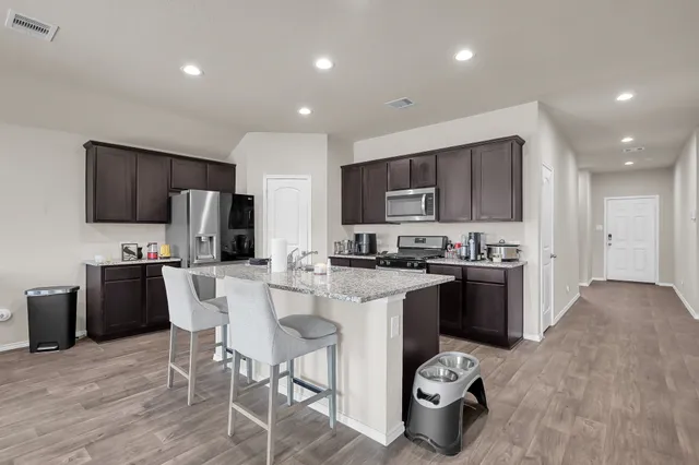 a kitchen with stainless steel appliances kitchen island granite countertop a sink dishwasher a refrigerator and a microwave