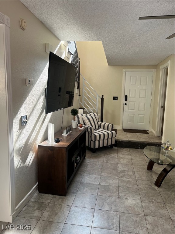 Living area featuring a textured ceiling, stairway, and baseboards