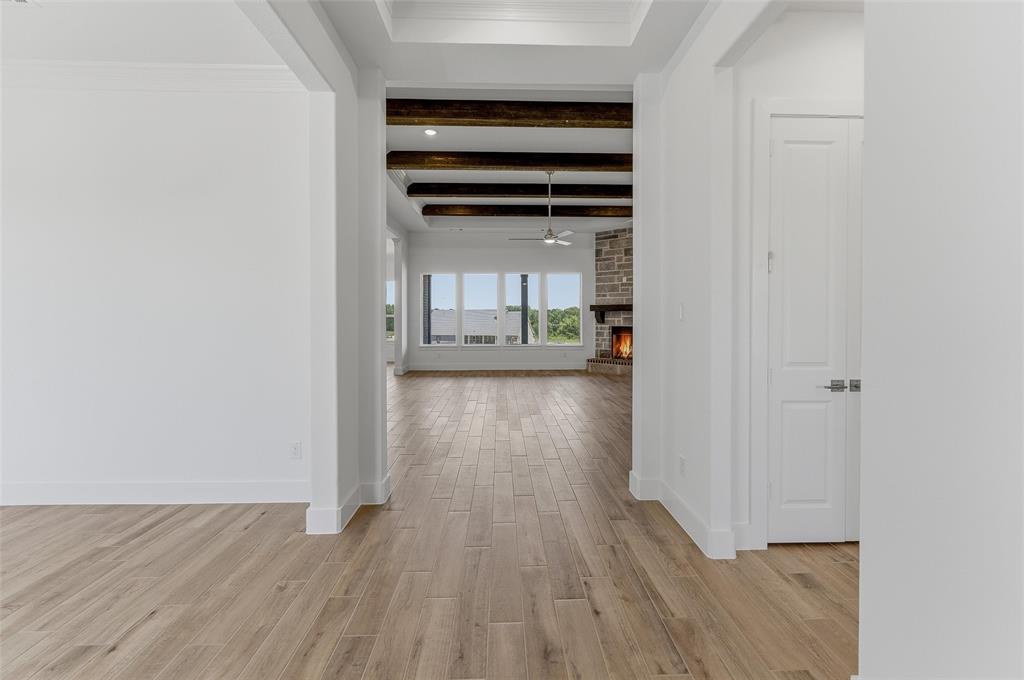 815 Vly Rdg Road Van Alstyne, TX 75495 - Photo 5 of 29 Expansive living area with wood-finish flooring, exposed ceiling beams, a stone-clad fireplace, and multiple windows