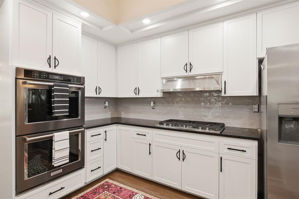 2351 Northeast Coachman Road Clearwater, FL 33765 - Photo 19 of 47 a kitchen with granite countertop white cabinets and stainless steel appliances