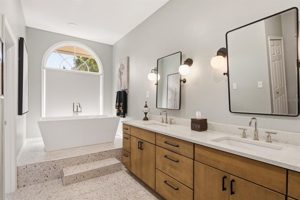 2351 Northeast Coachman Road Clearwater, FL 33765 - Photo 27 of 47 a bathroom with double vanity sinks a large mirror and a bathtub