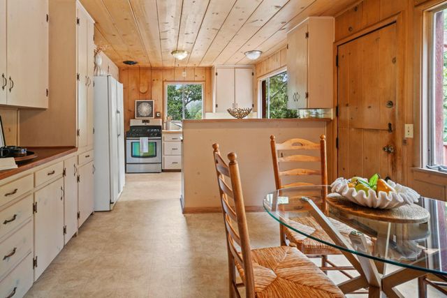 a kitchen with stainless steel appliances kitchen island granite countertop a refrigerator a stove a dining table and chairs with wooden floor