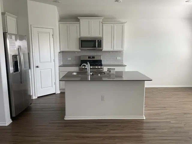 a kitchen with stainless steel appliances granite countertop a refrigerator stove a sink and a microwave