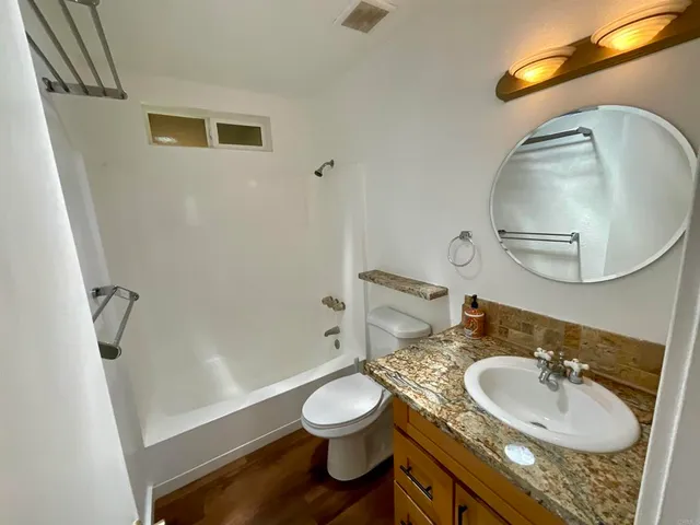 a bathroom with a granite countertop sink a mirror and a shower