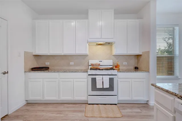 a kitchen with a stove and white cabinets