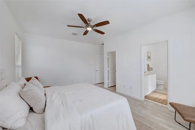 a bedroom with a large bed and wooden floor