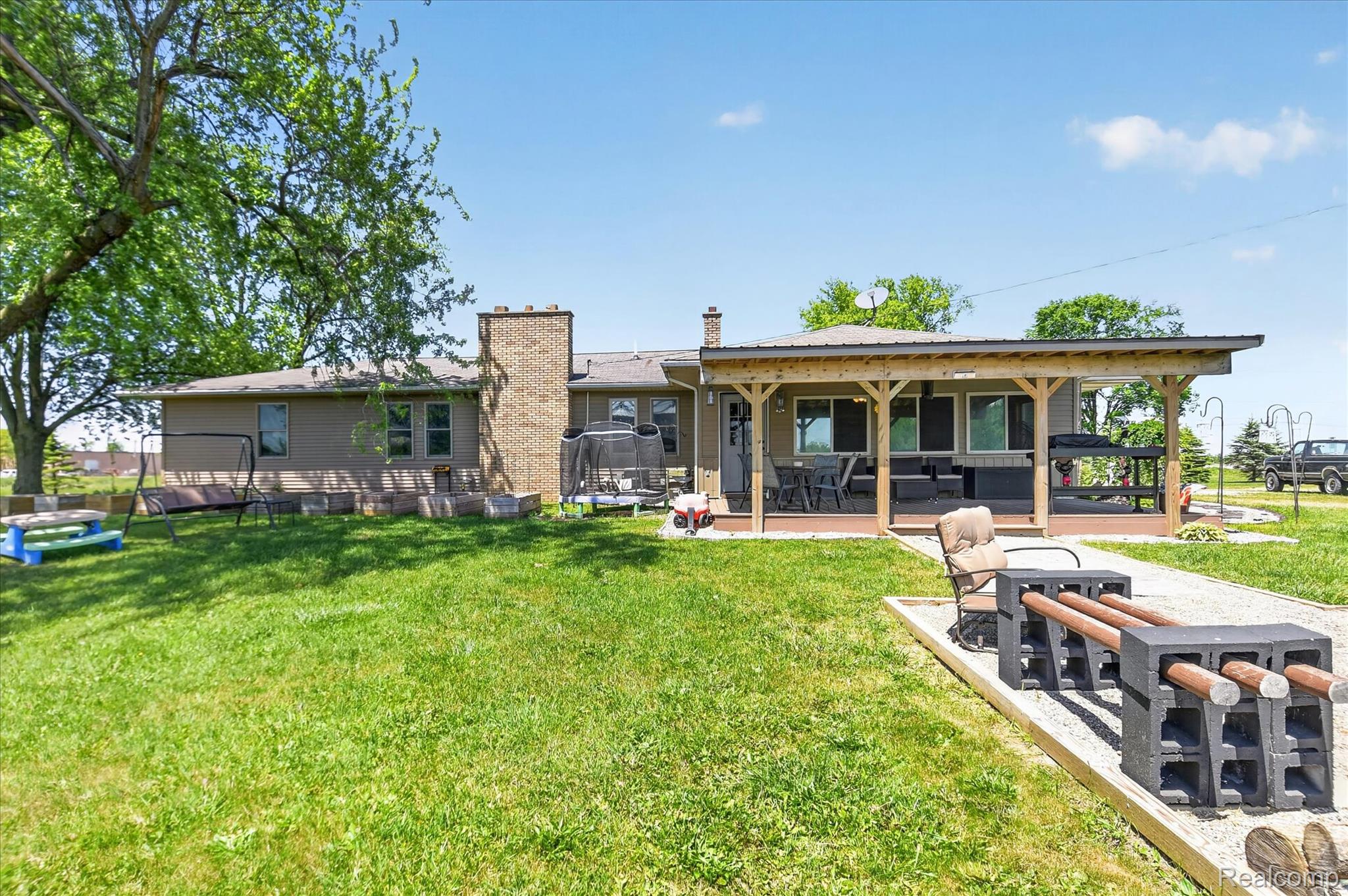 3949 West Burns Line Road Brown City, MI 48416 - Photo 68 of 70 Expansive backyard featuring a covered patio with wood support beams, a brick chimney, and mature trees