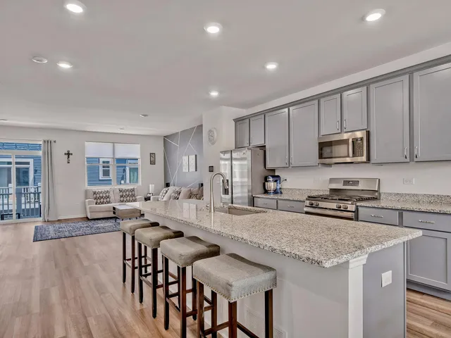 a kitchen with granite countertop a stove a sink a microwave a dining table and chairs