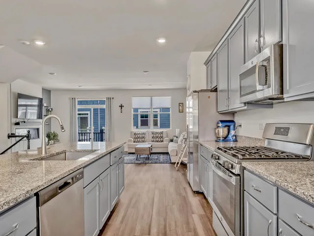 a kitchen with stainless steel appliances granite countertop a lot of counter space and wooden floors