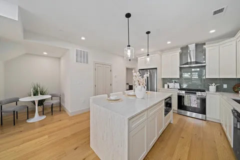 a large white kitchen with lots of counter space a sink appliances and chairs