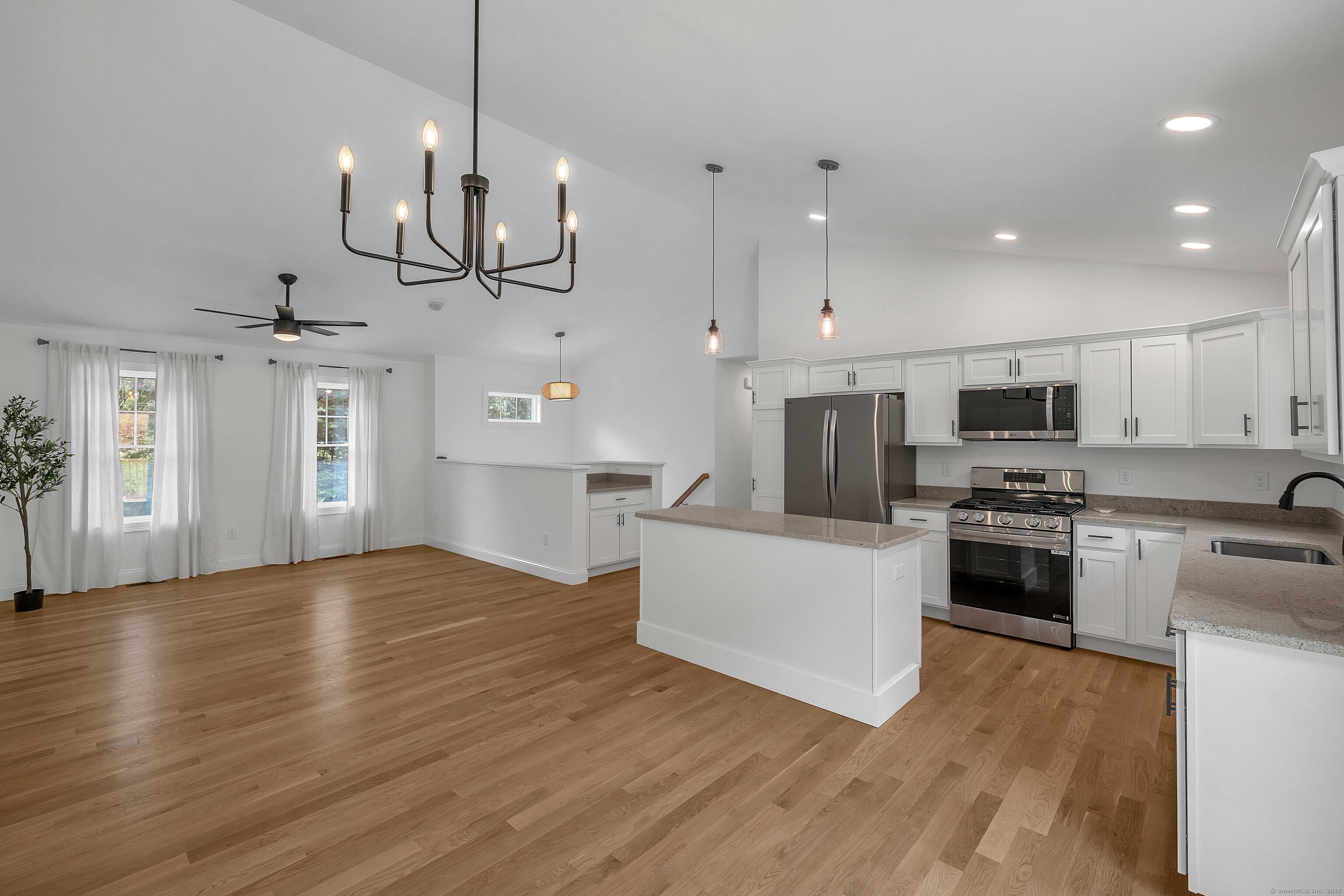 4 Lake Of Isles Road North Stonington, CT 06359 - Photo 11 of 23 a large kitchen with stainless steel appliances granite countertop a stove a sink dishwasher a refrigerator and a dining table with wooden floor