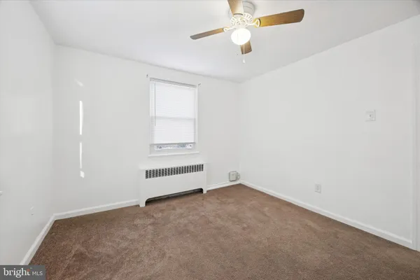 an empty room with a window and ceiling fan