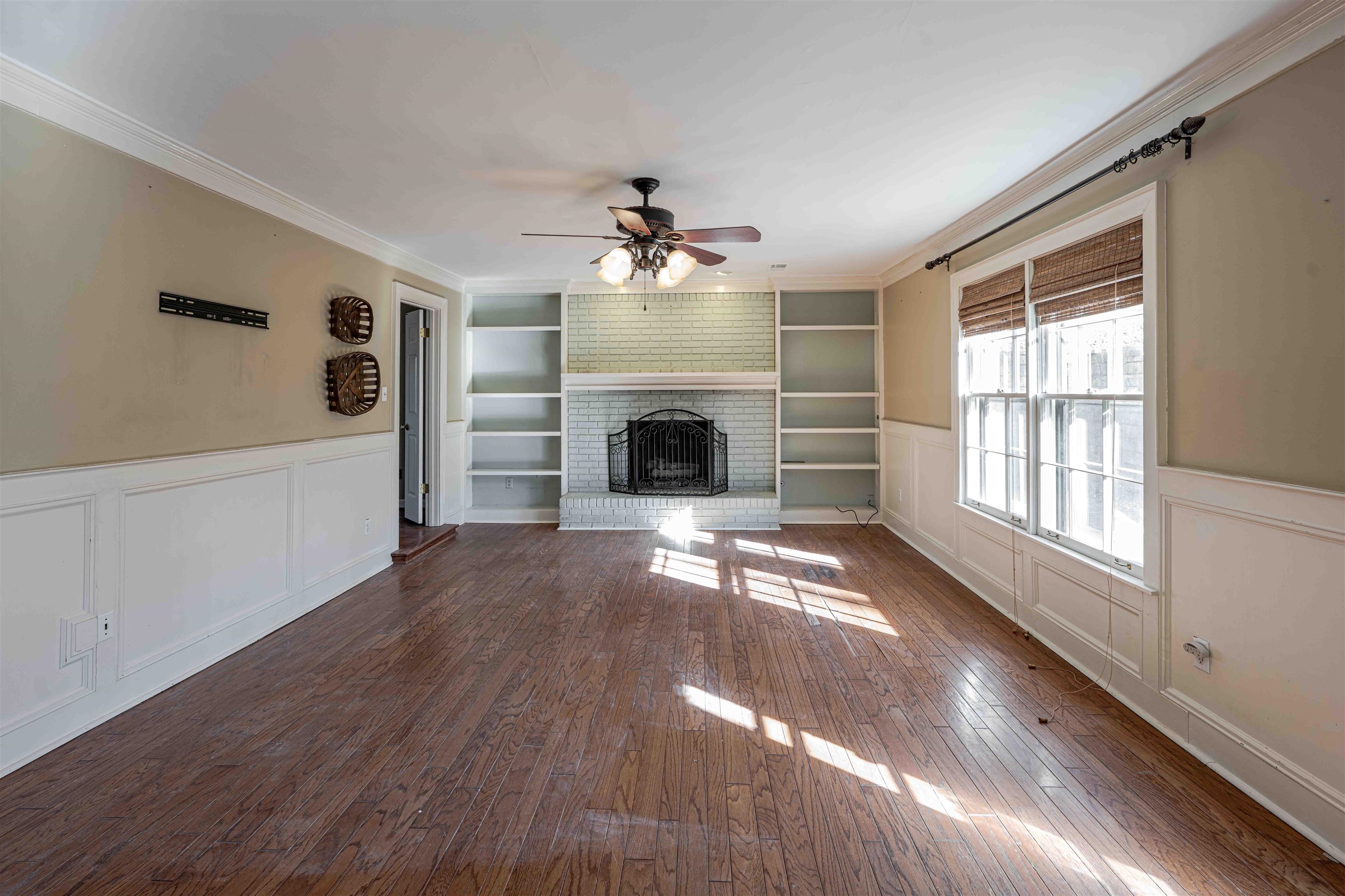 8883 Farmoor Road Germantown, TN 38139 - Photo 16 of 34 Unfurnished living room with a wainscoted wall, a decorative wall, crown molding, dark wood-type flooring, and a fireplace