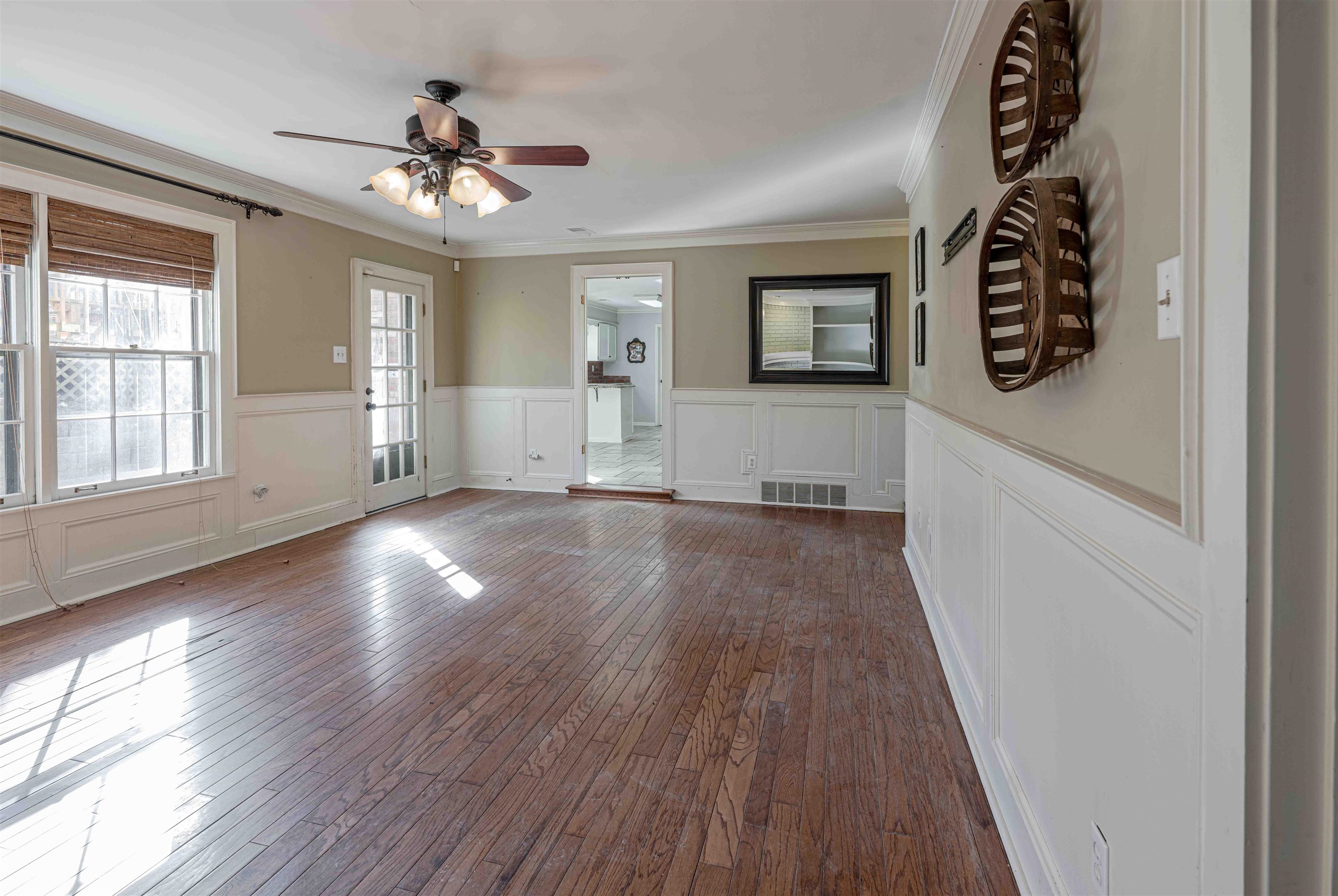 8883 Farmoor Road Germantown, TN 38139 - Photo 17 of 34 Unfurnished living room featuring a wainscoted wall, hardwood / wood-style floors, crown molding, a ceiling fan, and a decorative wall