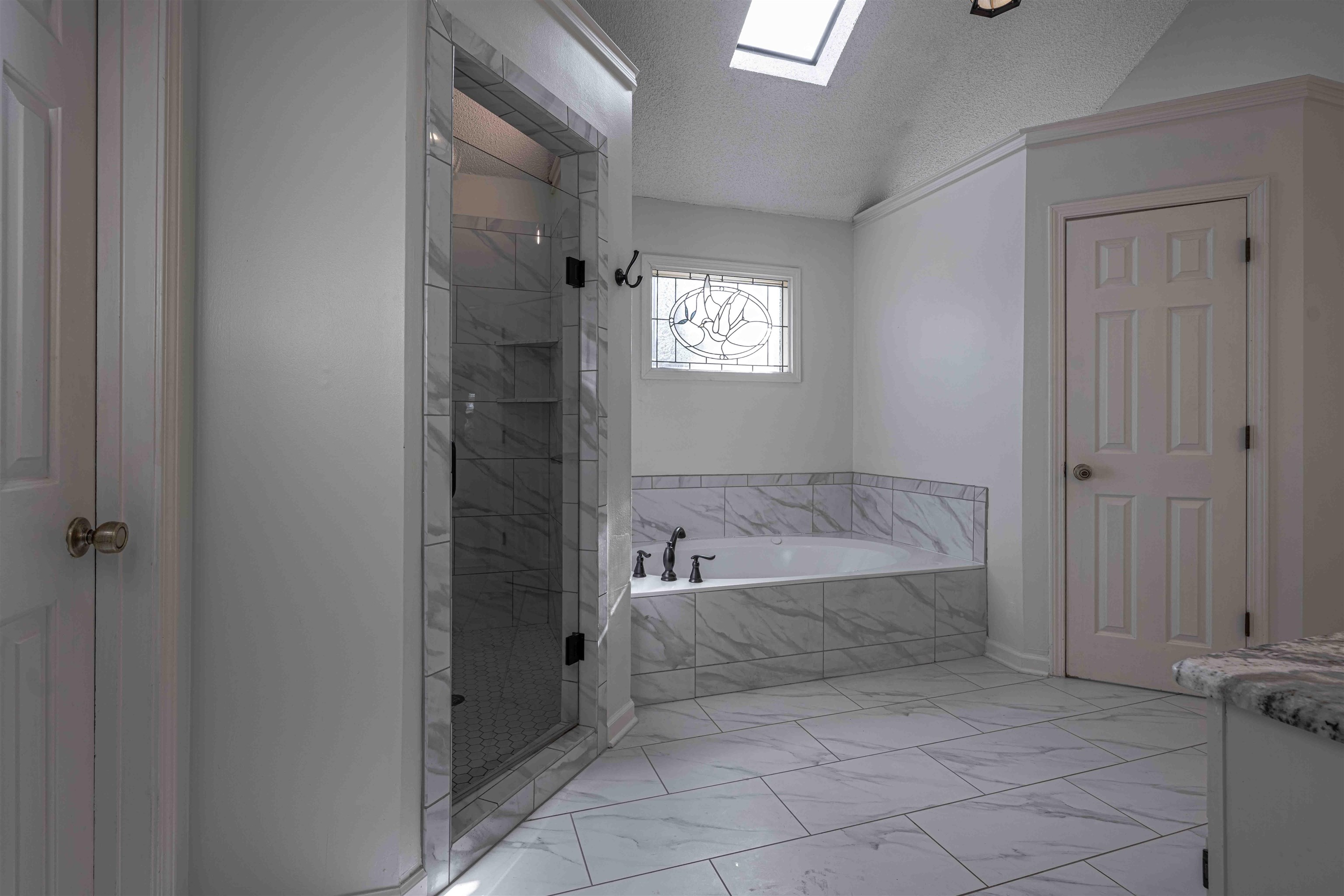 8883 Farmoor Road Germantown, TN 38139 - Photo 23 of 34 Full bath featuring light marble finish flooring, vanity, a skylight, a bath, and a textured ceiling