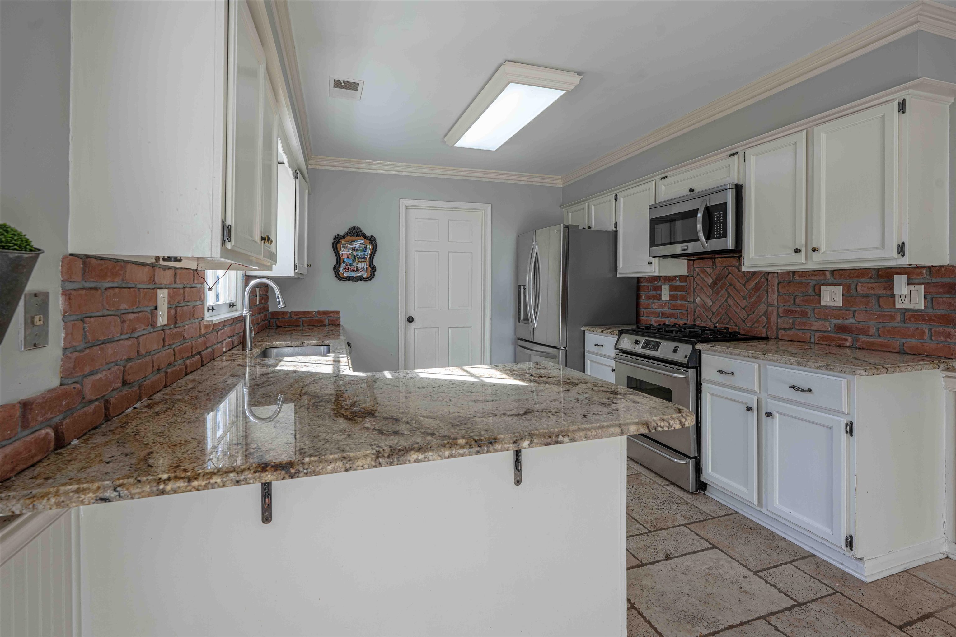 8883 Farmoor Road Germantown, TN 38139 - Photo 9 of 34 Kitchen with a peninsula, white cabinets, appliances with stainless steel finishes, and ornamental molding