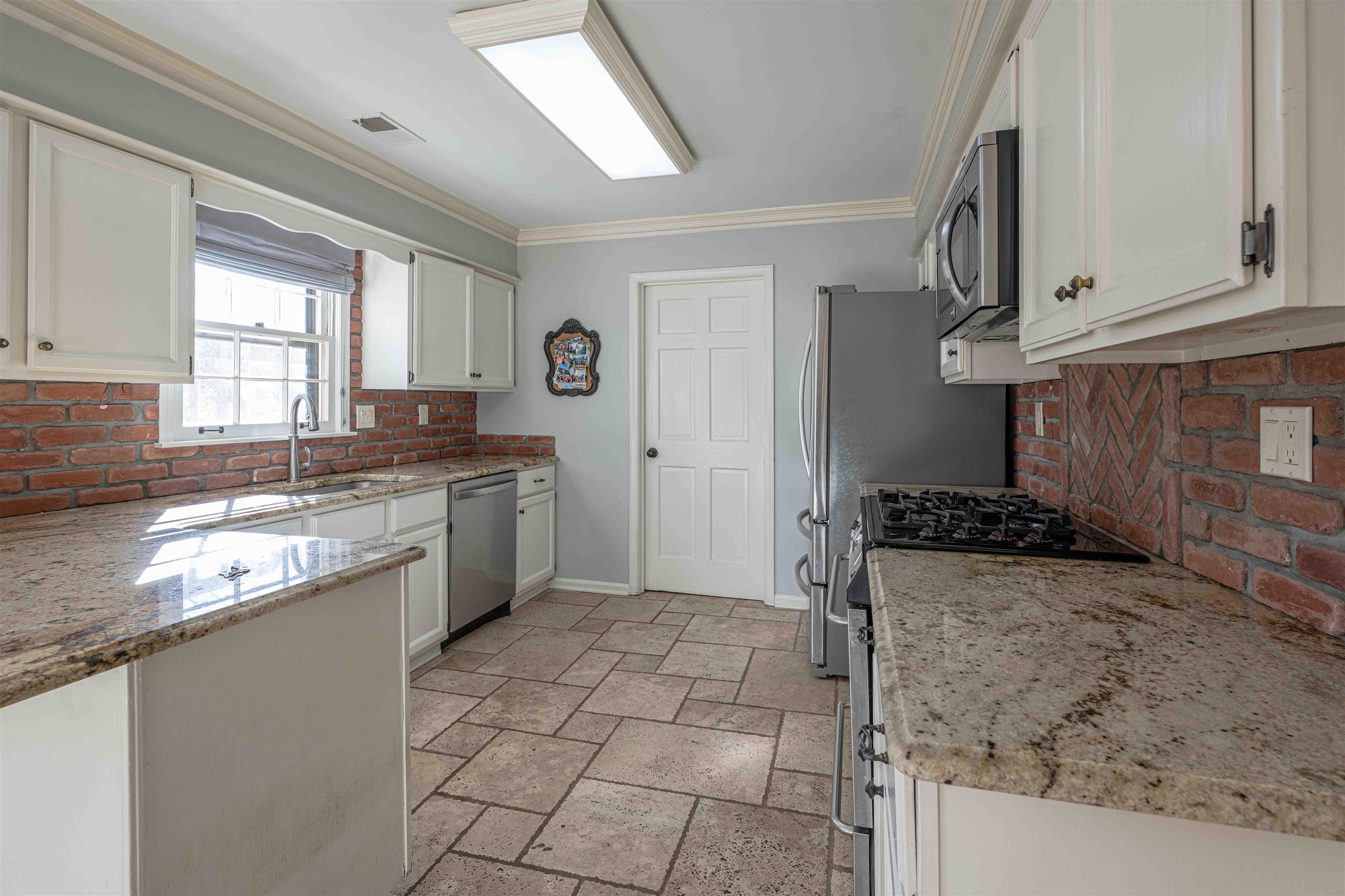 8883 Farmoor Road Germantown, TN 38139 - Photo 10 of 34 Kitchen with white cabinets, crown molding, backsplash, appliances with stainless steel finishes, and light stone counters