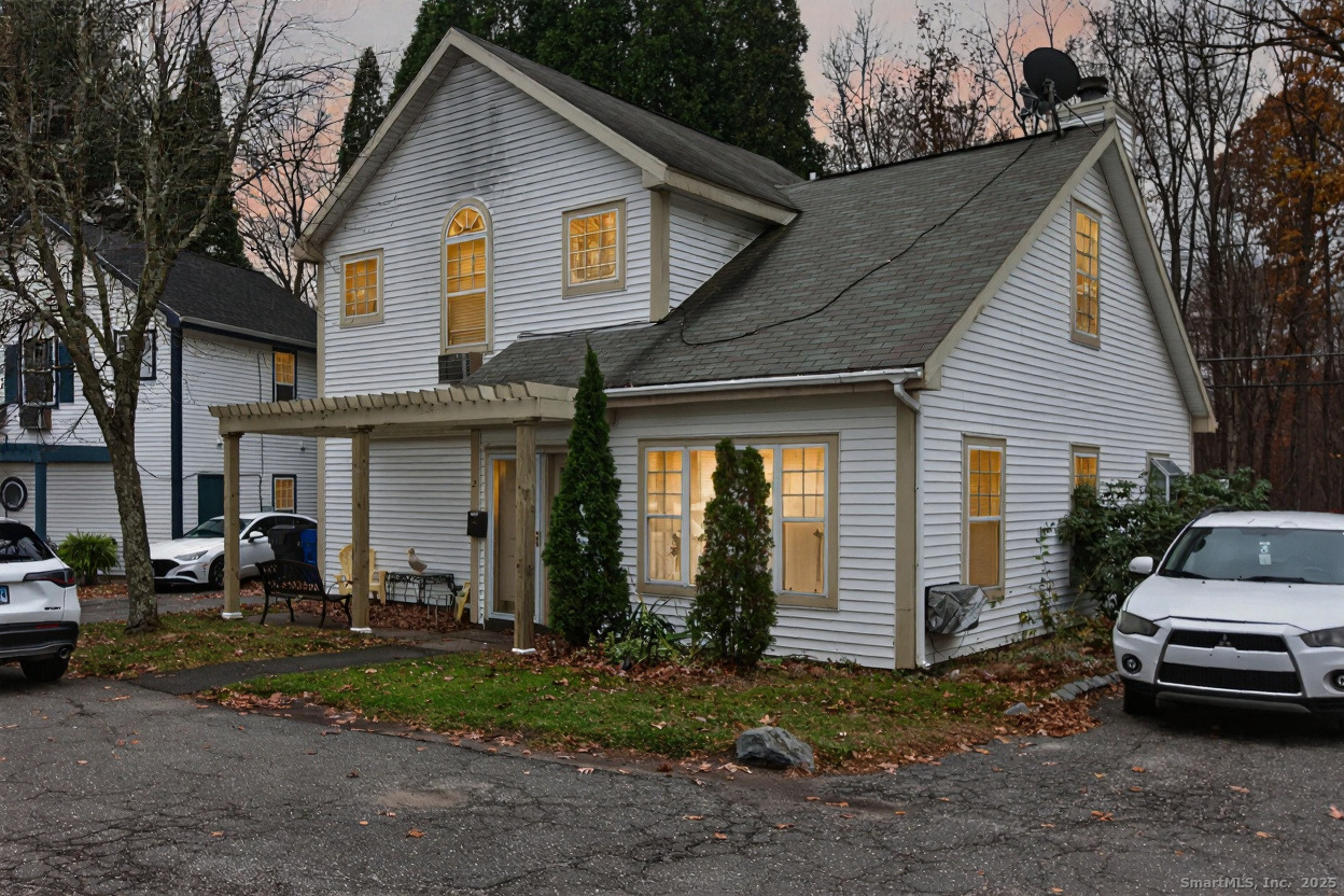 a view of a white house next to a yard and cars parked