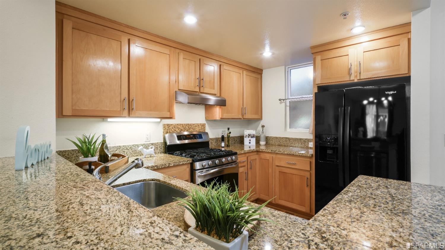 a kitchen with granite countertop a sink stainless steel appliances and cabinets