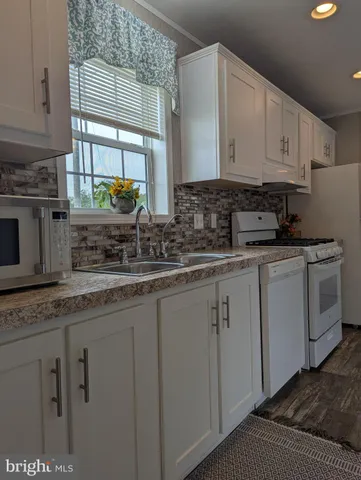 a kitchen with stainless steel appliances granite countertop a sink a stove and cabinets