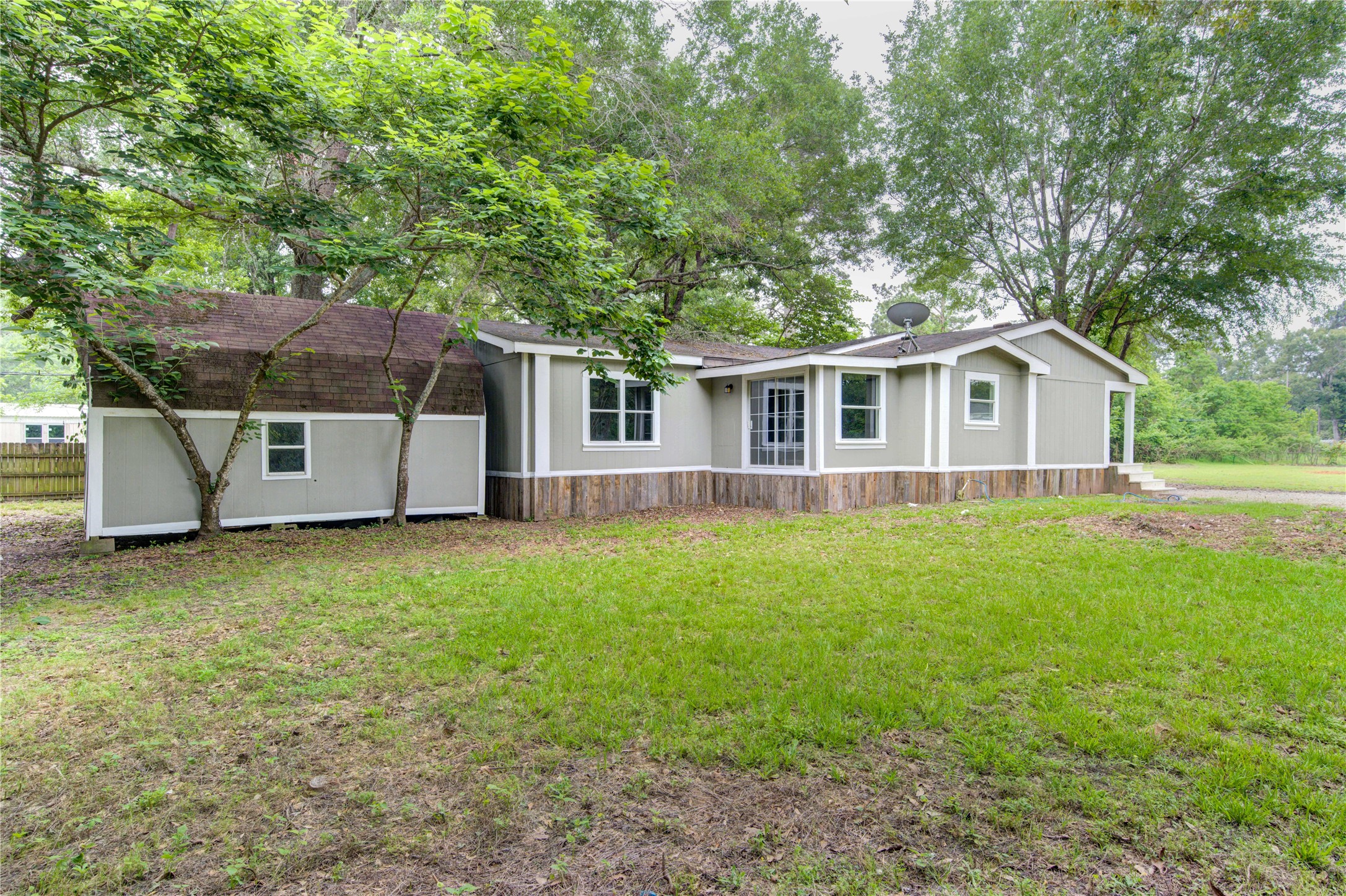 30226 Davis Street Magnolia, TX 77355 - Photo 46 of 50 Charming single-story home with a rustic exterior, nestled amidst lush greenery. Features a spacious yard and ample natural light from large windows. Ideal for those seeking peace and privacy.