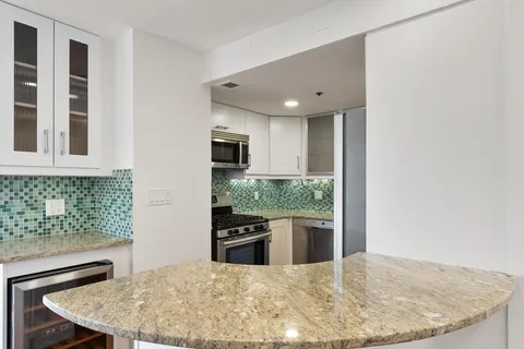 a kitchen with kitchen island stainless steel appliances a sink stove and refrigerator