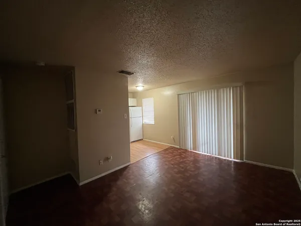 an empty room with wooden floor and windows with curtains