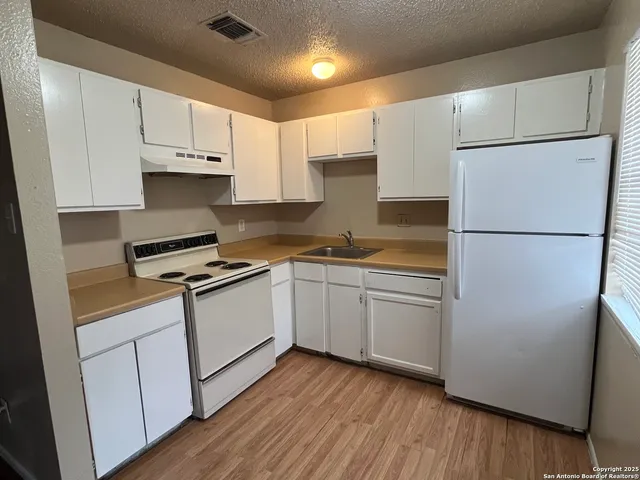 a kitchen with white cabinets and white appliances