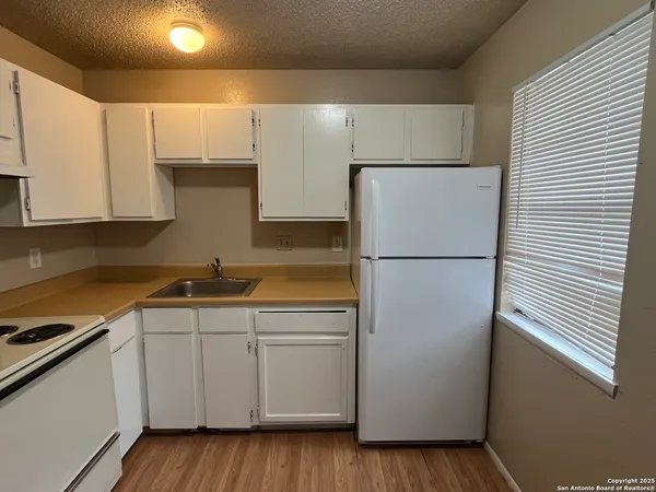 a kitchen with a sink a refrigerator and cabinets