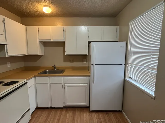 a kitchen with a sink a refrigerator and cabinets