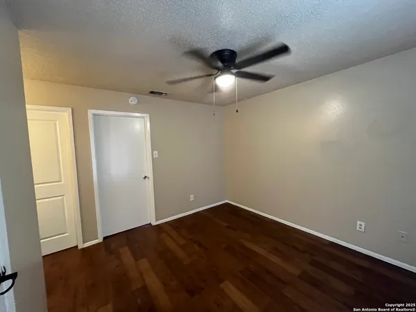 an empty room with wooden floor and fan