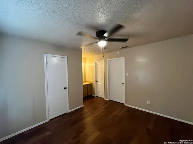 an empty room with wooden floor and a ceiling fan