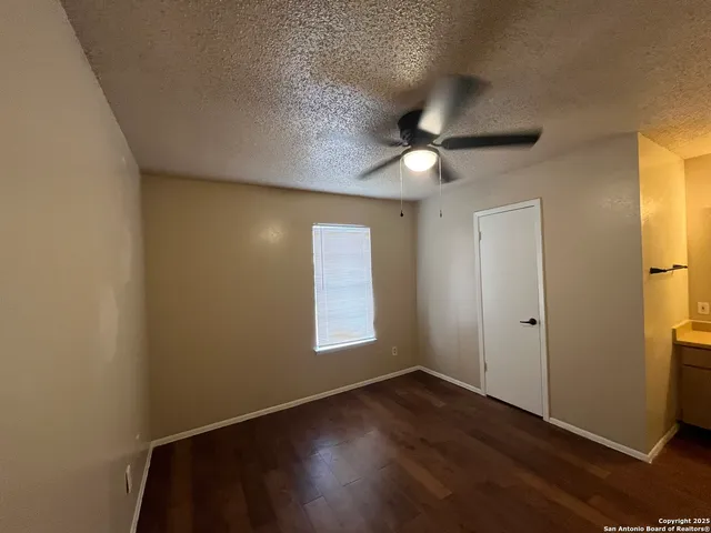 an empty room with wooden floor closet and windows