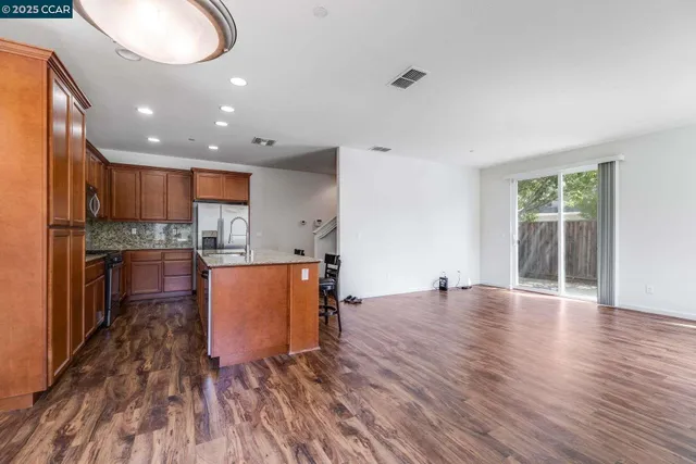 an open kitchen with kitchen island a sink dishwasher stove and oven with wooden floor