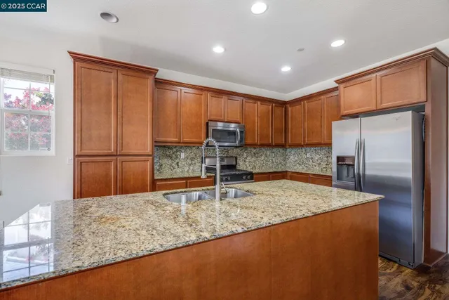 a kitchen with granite countertop a refrigerator and a sink