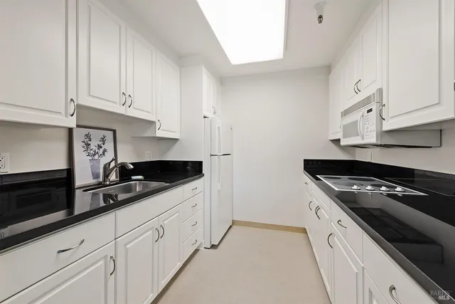 a kitchen with granite countertop white cabinets and black appliances