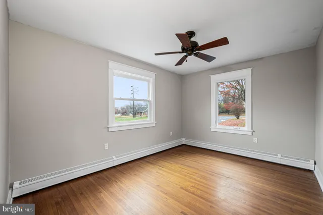 a view of empty room with wooden floor and fan