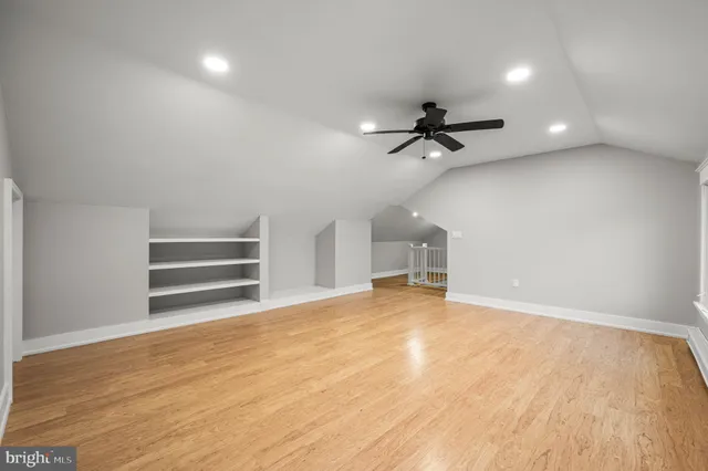 a view of an empty room with a ceiling fan and wooden floor