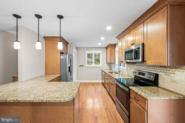 a kitchen with stainless steel appliances granite countertop a sink a stove top oven a refrigerator with wooden floor and cabinets