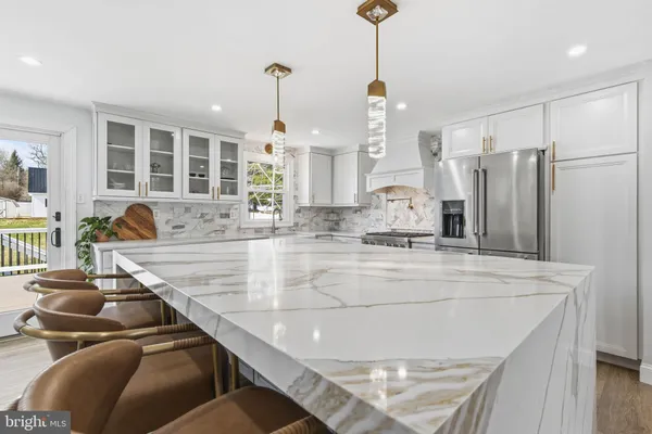 a large kitchen with kitchen island a large counter top stainless steel appliances and windows
