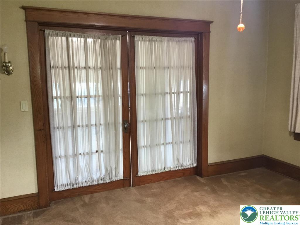 1105 Main Street Slatington, PA 18080 - Photo 9 of 31 French doors with sheer curtains divide this inviting living area, featuring warm wood trim.
