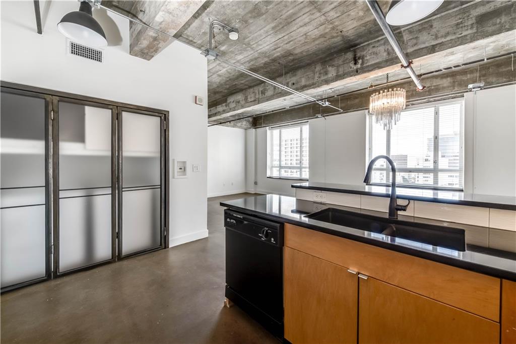 710 Colorado Street, Unit G9 Austin, TX 78701 - Photo 5 of 25 Industrial chic design showcases an open-plan kitchen and living area with exposed concrete ceilings and city views.