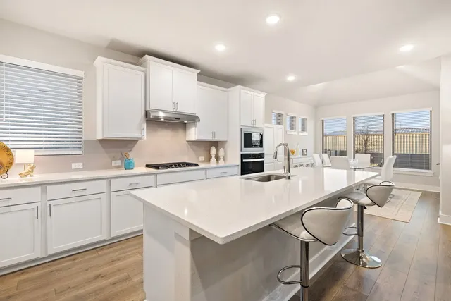 a large kitchen with kitchen island a large counter top space a sink stainless steel appliances and cabinets