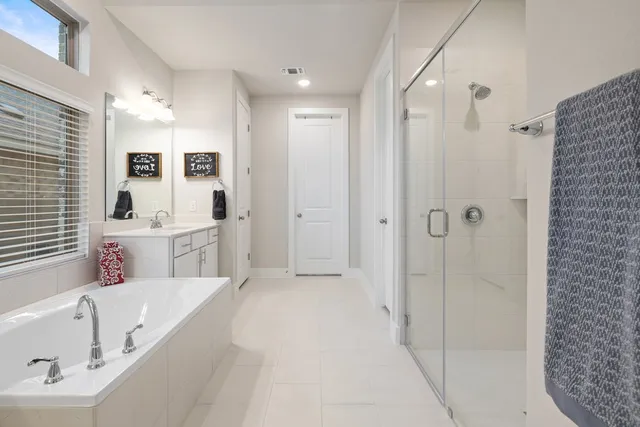 a large white bathroom with a tub sink shower and mirror