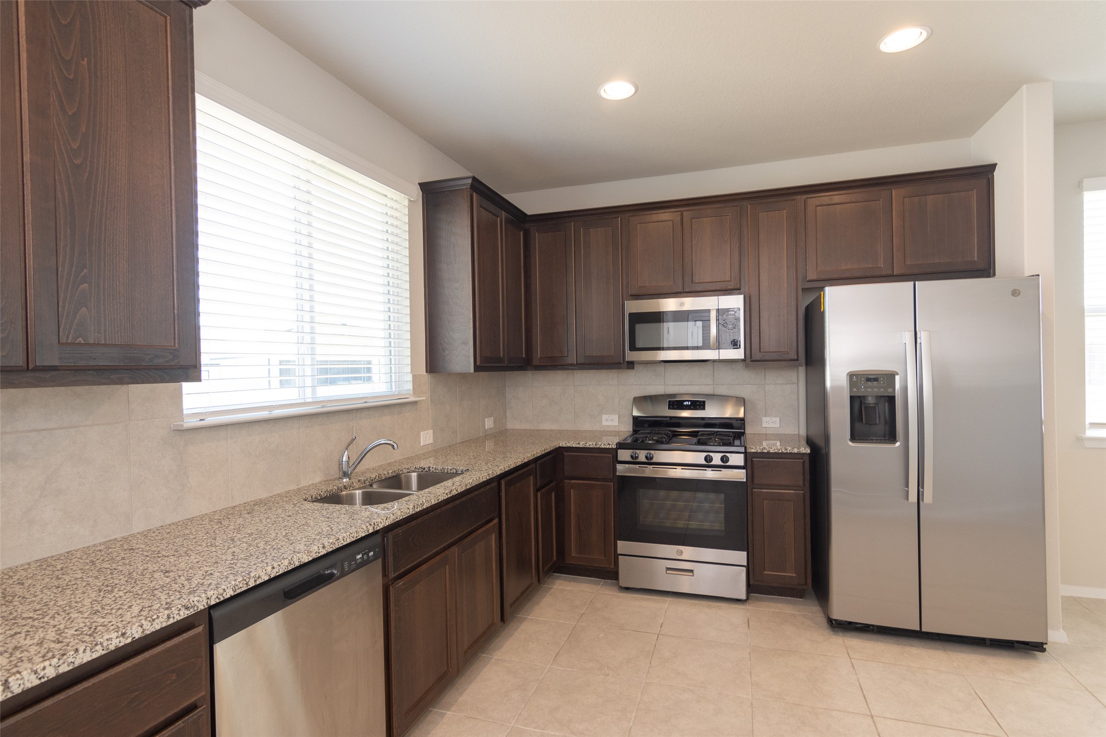 350 Fabion Street Kyle, TX 78640 - Photo 11 of 33 a kitchen with stainless steel appliances granite countertop a sink stove and refrigerator