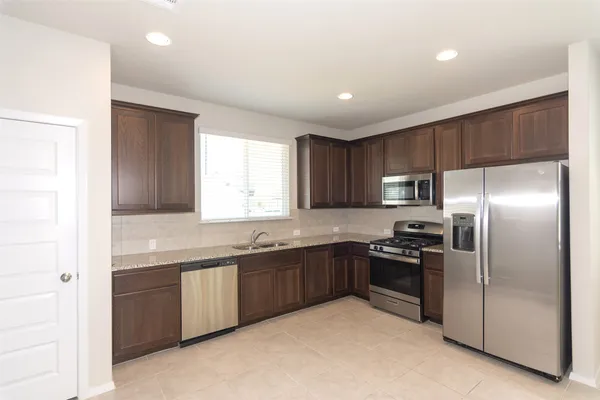 a kitchen with stainless steel appliances granite countertop a sink and a refrigerator